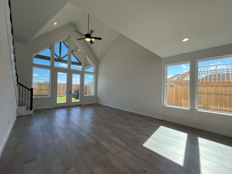 The family room boasts a vaulted ceiling that enhances the sense of space and openness. Large windows allow natural light to fill the room, creating a bright and inviting atmosphere.