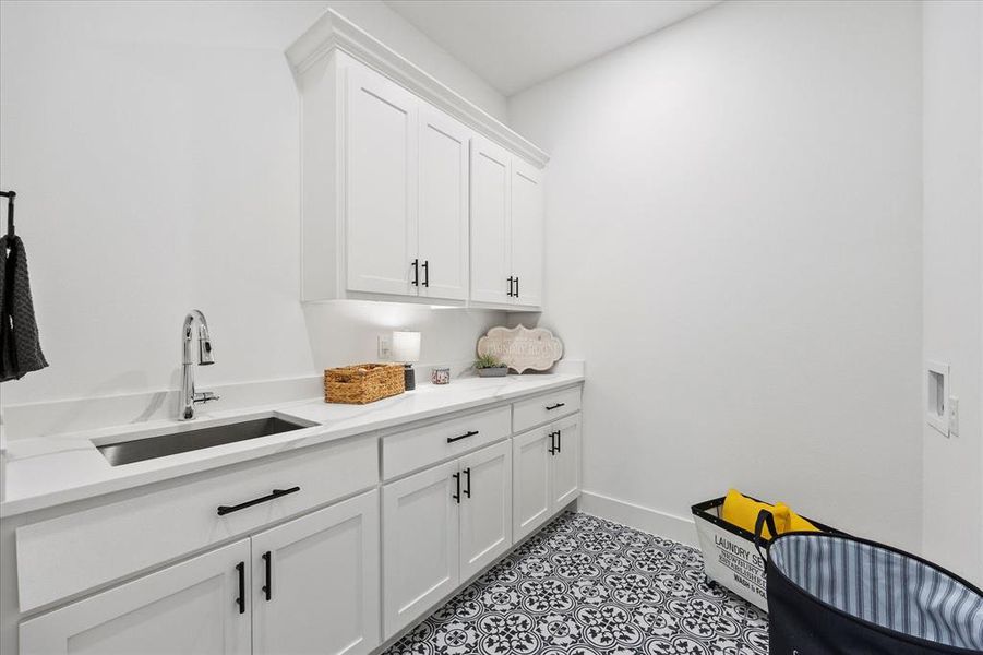 Washroom featuring cabinets, hookup for a washing machine, light tile patterned floors, and sink