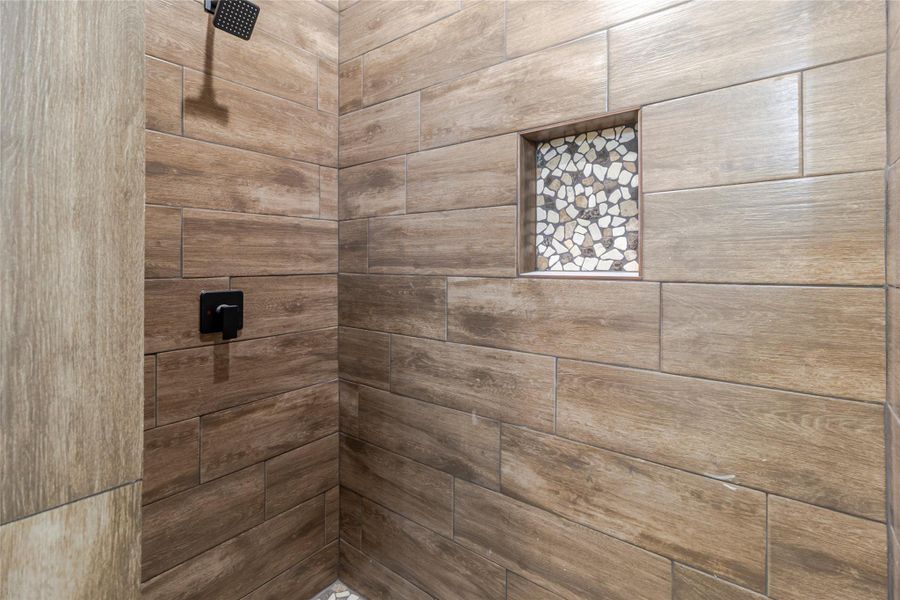 The primary shower is wrappedin floor too ceiling tile surround,with a recessed niche and matte black fixtures. The primary shower is wrappedin floor too ceiling tile surround,with a recessed niche and matte black fixtures.