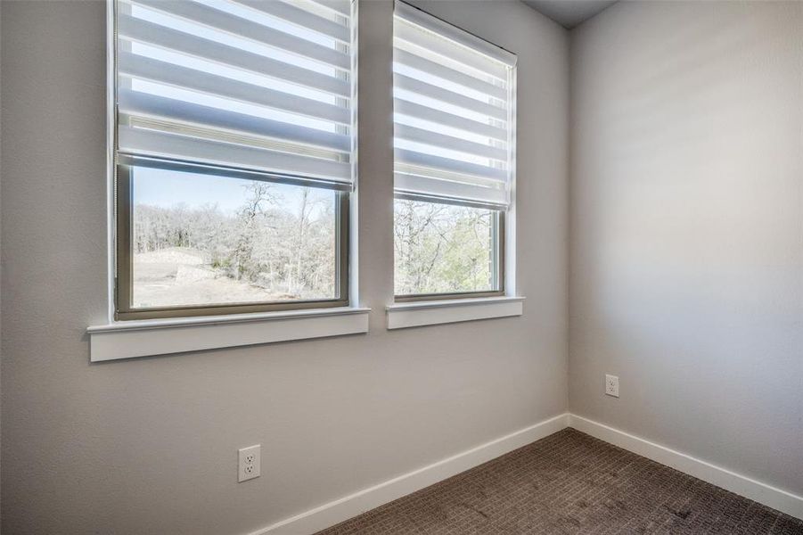 Spare room featuring baseboards and dark carpet