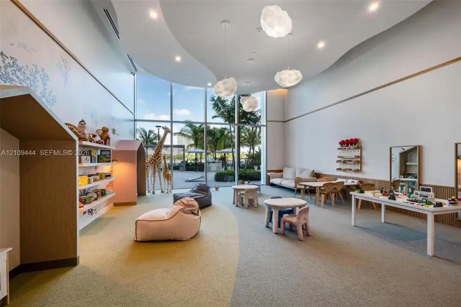 Floor-to-ceiling windows, sculptural pendant lighting, recessed cove ceiling, built-in shelving niches, and neutral carpeted flooring