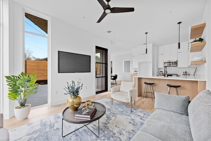 Living room with healthy amount of natural light, light wood-type flooring, and ceiling fan