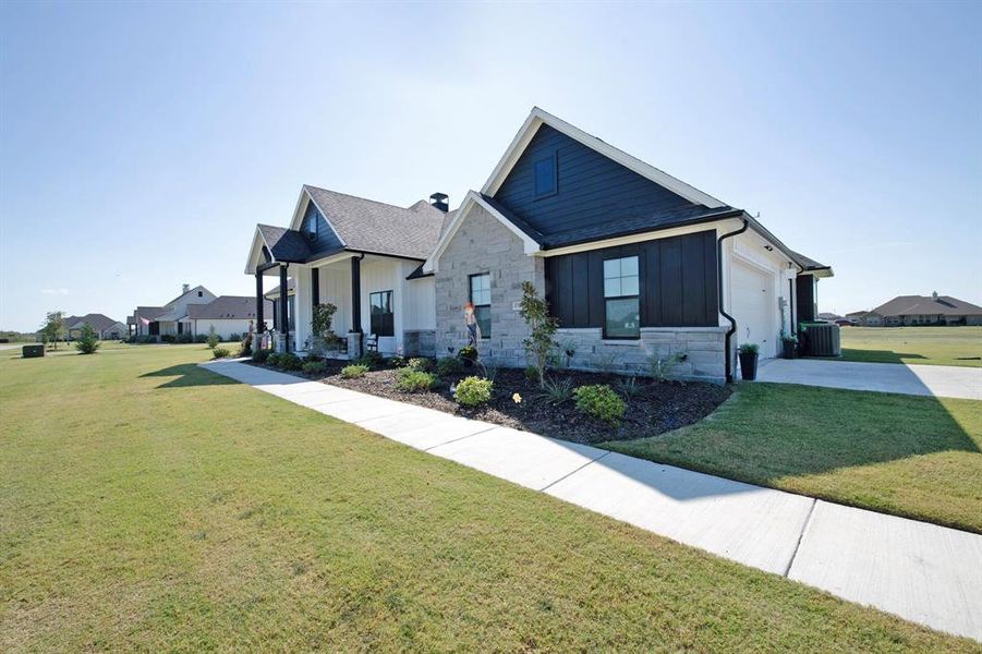 View of front of house featuring stone siding, a front lawn, a garage, and board and batten siding