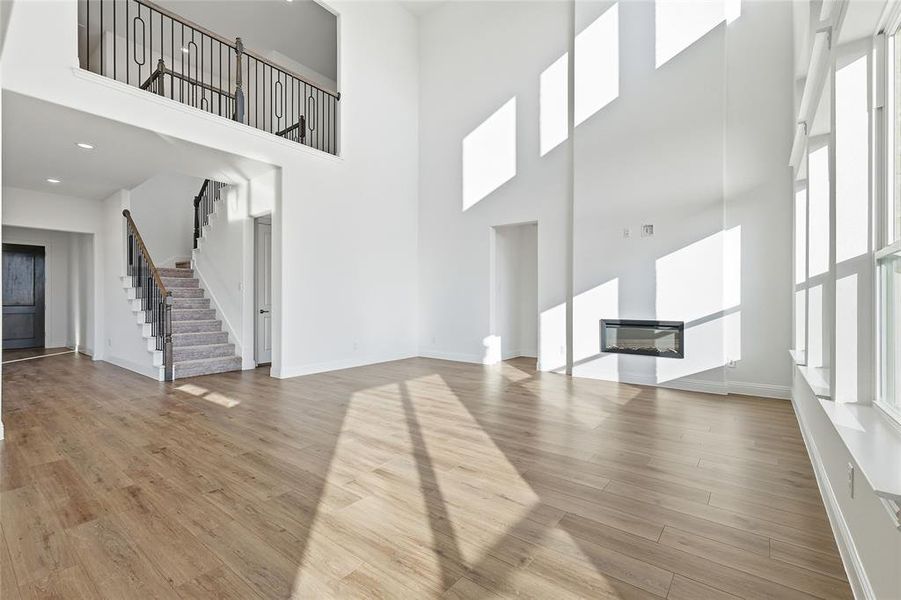 Unfurnished living room with a glass covered fireplace, a high ceiling, and light wood finished floors Unfurnished living room with a glass covered fireplace, a high ceiling, and light wood finished floors