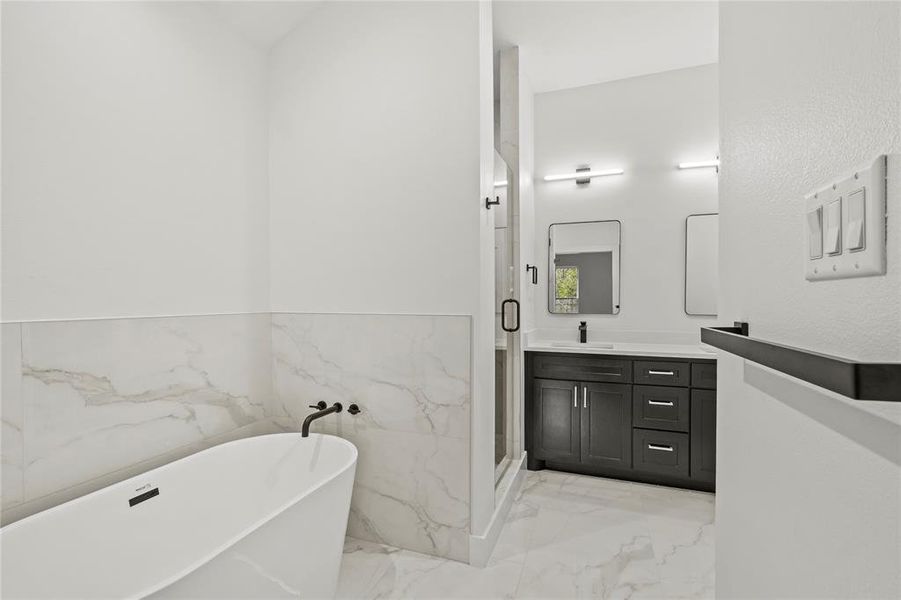 Bathroom featuring vanity, separate shower and tub, and tile walls