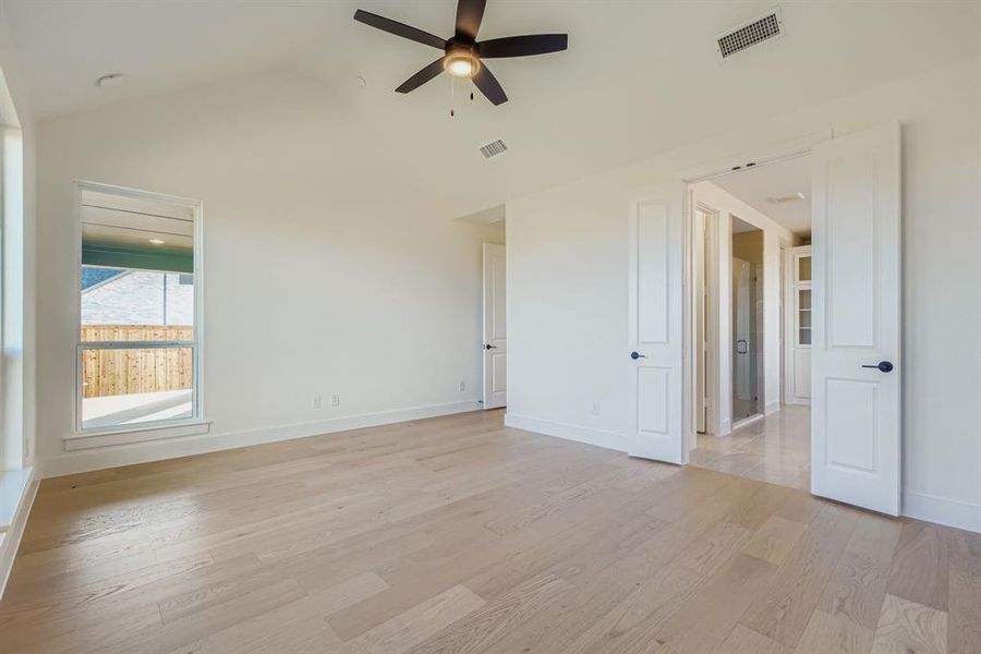 Unfurnished bedroom with lofted ceiling, light wood-type flooring, and ceiling fan Unfurnished bedroom with lofted ceiling, light wood-type flooring, and ceiling fan