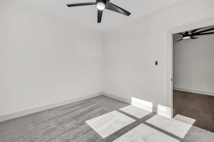 Carpeted spare room with ceiling fan and baseboards