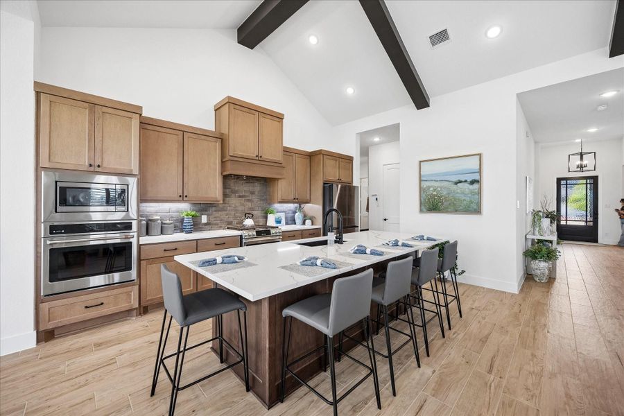 Chef's kitchen featuring custom soft close cabinetry, upgraded stainless steel appliances including double ovens, and a spacious granite countertop island perfect for family meals and entertaining.