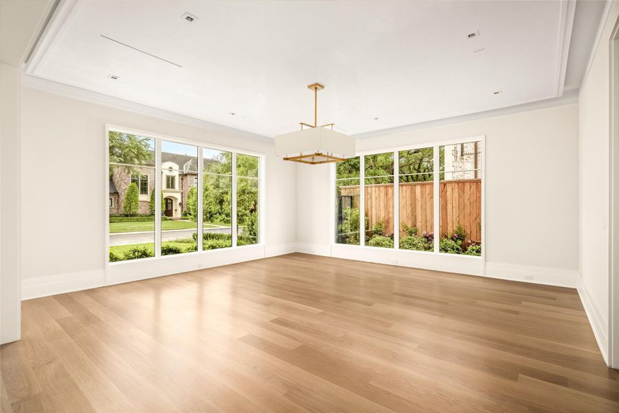 Formal living framed by floor-to-ceiling windows, featuring a tray ceiling with cove lighting, plaster-finished walls, and a statement Visual Comfort chandelier.