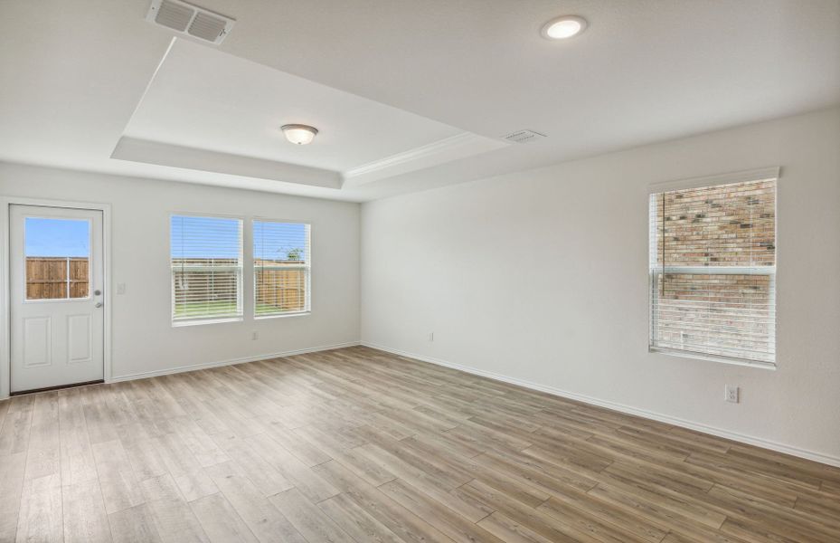 Spacious gathering room with tray ceiling and access to backyard