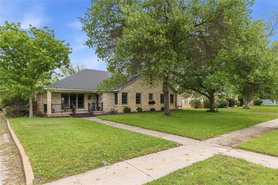 Stone-clad exterior featuring a covered front porch with dark railings and steps Stone-clad exterior featuring a covered front porch with dark railings and steps