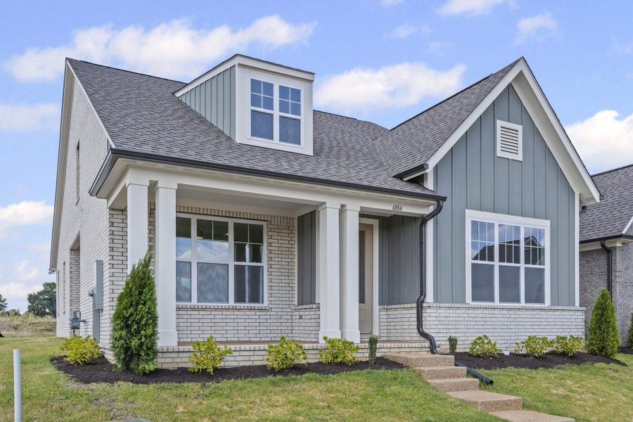 View of front facade featuring brick siding, a porch, roof with shingles, and a front lawn View of front facade featuring brick siding, a porch, roof with shingles, and a front lawn