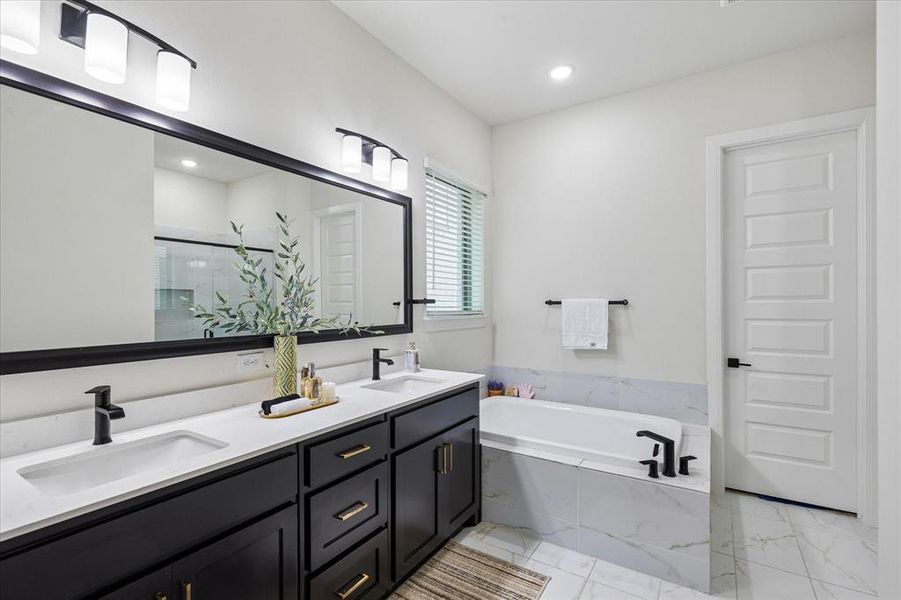 Bathroom featuring a double vanity with dark cabinetry, white countertops, and matte black fixtures Bathroom featuring a double vanity with dark cabinetry, white countertops, and matte black fixtures