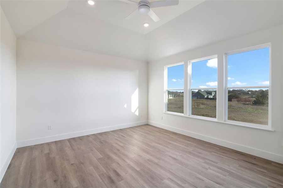 Empty room with light hardwood / wood-style flooring, ceiling fan, and lofted ceiling