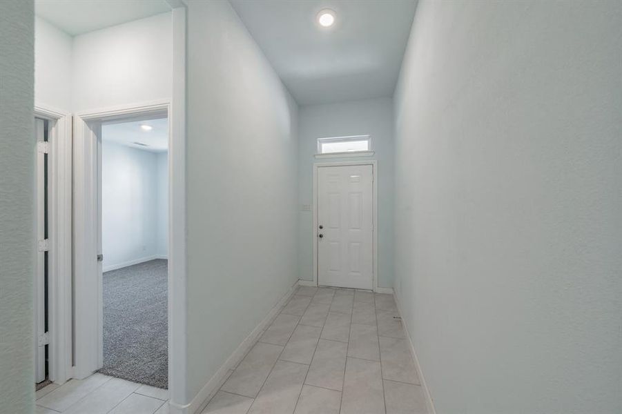 Hall with light tile patterned floors and baseboards Hall with light tile patterned floors and baseboards