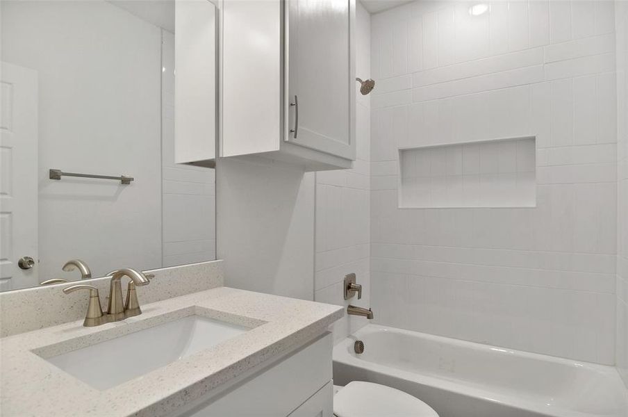 Full bathroom featuring tiled shower / bath combo, toilet, and vanity