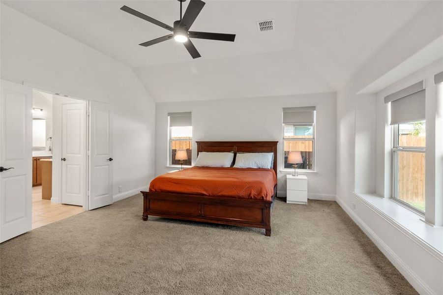 Bedroom with light carpet, a ceiling fan, lofted ceiling, and connected bathroom