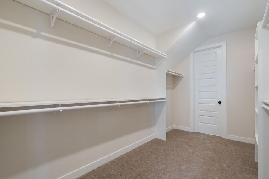 Spacious walk-in closet featuring built-in shelving, hanging rods, recessed lighting, and carpet flooring Spacious walk-in closet featuring built-in shelving, hanging rods, recessed lighting, and carpet flooring
