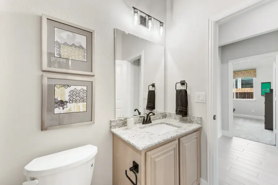 Bathroom with granite vanity, large mirror, and light wood cabinets with black fixtures