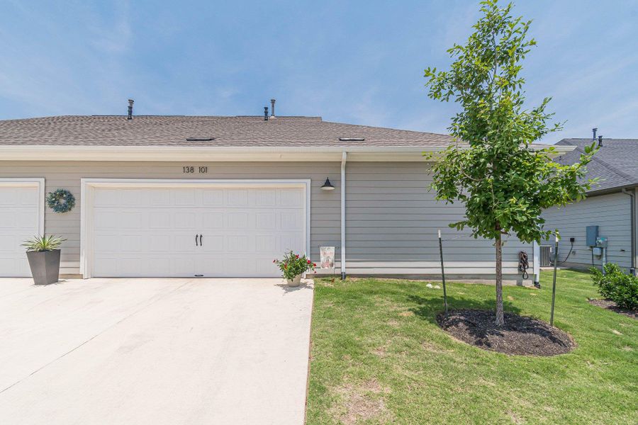 View of front facade featuring concrete driveway, a front lawn, and roof with shingles