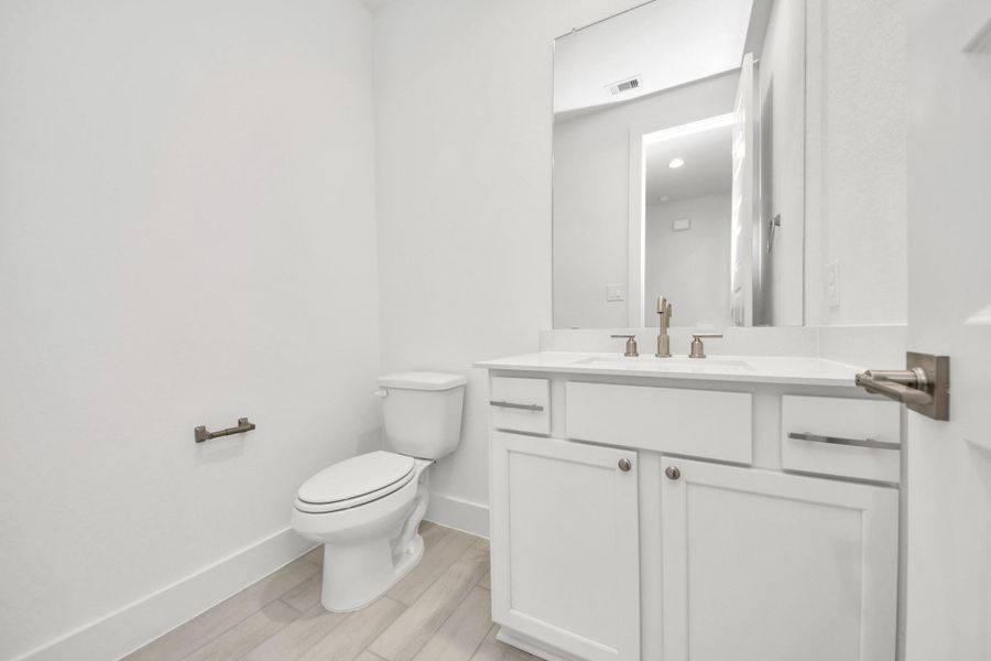 Sophisticated half bathroom adorned with contemporary finishes. The elegant 5-panel door welcomes you to a space where style meets functionality. Notice the sleek hardware accents that add a touch of modern charm. The vanity boasts light-colored countertops, beautifully complemented by a tasteful vanity light, creating a well-lit and inviting atmosphere. Sophisticated half bathroom adorned with contemporary finishes. The elegant 5-panel door welcomes you to a space where style meets functionality. Notice the sleek hardware accents that add a touch of modern charm. The vanity boasts light-colored countertops, beautifully complemented by a tasteful vanity light, creating a well-lit and inviting atmosphere.