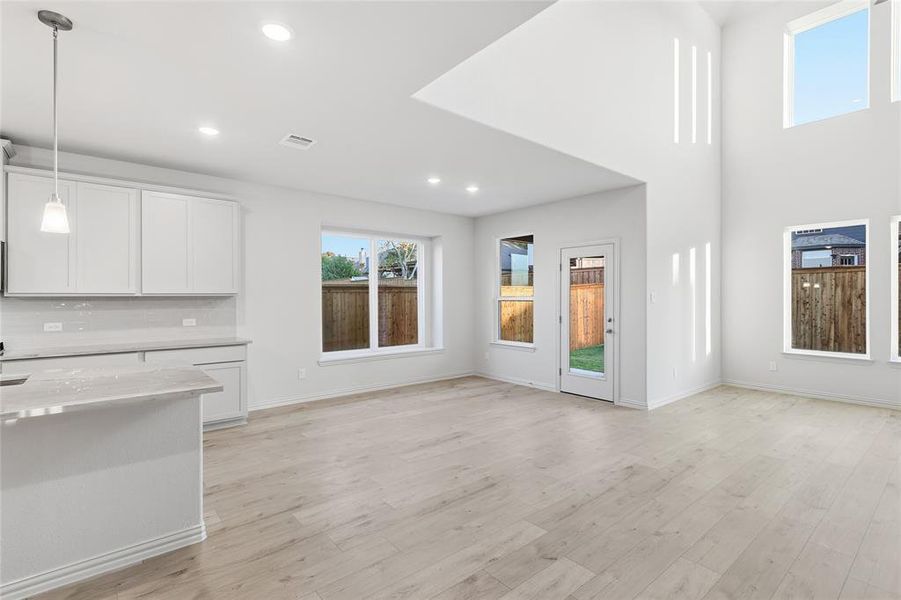 Unfurnished living room with light wood-style floors, recessed lighting, and a high ceiling