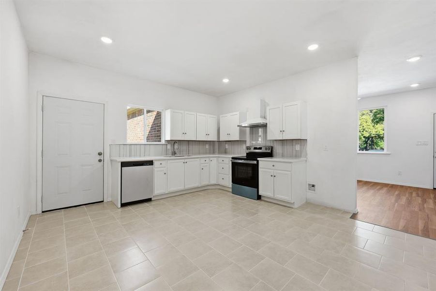 Eat-in kitchen with decorative backsplash, appliances with stainless steel finishes, light countertops, white cabinets, and recessed lighting