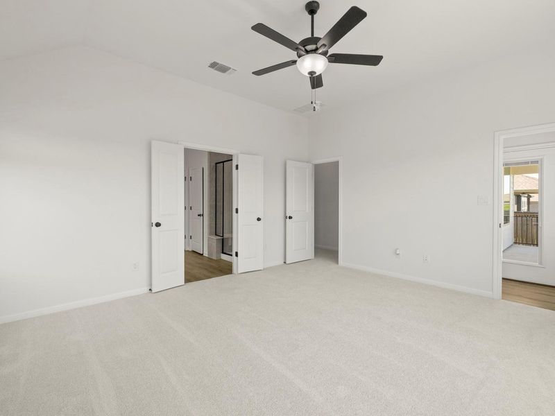 Expansive room featuring light-colored carpeting, vaulted ceiling, and a ceiling fan with integrated lighting