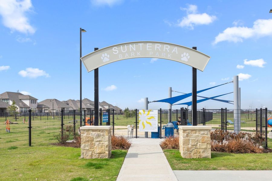 The community dog park includes fenced play areas, shade structures, and seating for pet owners.