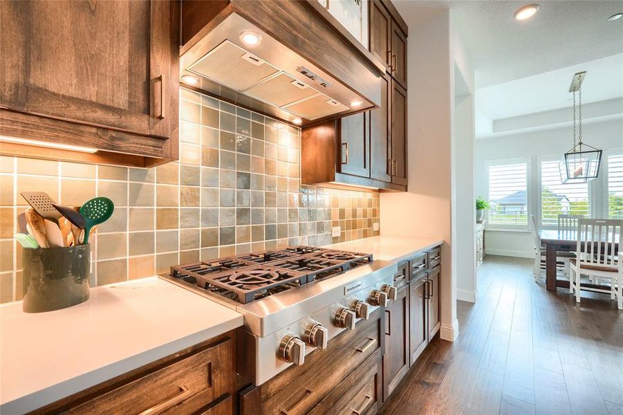 Kitchen featuring stainless steel gas cooktop, recessed lighting, backsplash, dark wood-style flooring, and light stone counters