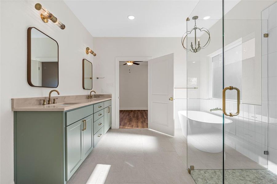 Full bathroom featuring a ceiling fan, a freestanding tub, double vanity, a stall shower, and a chandelier Full bathroom featuring a ceiling fan, a freestanding tub, double vanity, a stall shower, and a chandelier