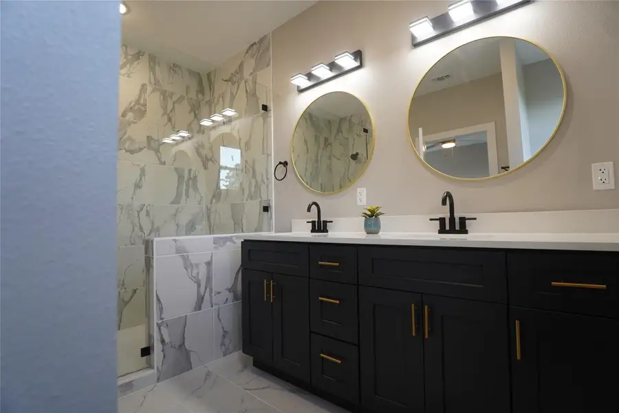 Double vanity sink , gorgeous dark blue cabinets assembled with fine white countertops. Next to a high-class shower with tempered glass.