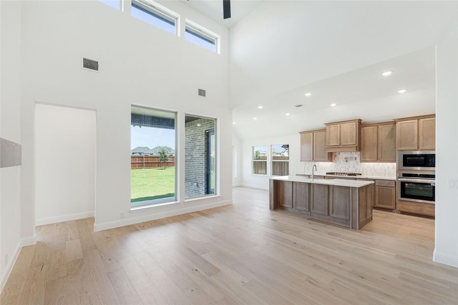Open living area with high ceilings and kitchen featuring wood cabinets, center island, and hardwood floors