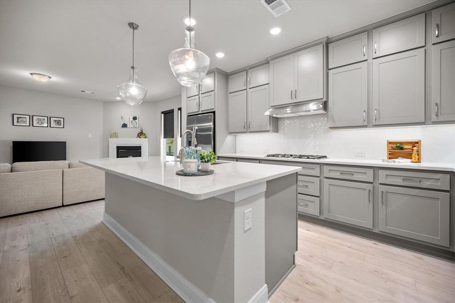 Kitchen with gray cabinetry, decorative backsplash, light countertops, and recessed lighting Kitchen with gray cabinetry, decorative backsplash, light countertops, and recessed lighting