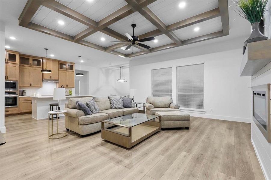 Living room featuring beamed ceiling, coffered ceiling, and light hardwood / wood-style flooring