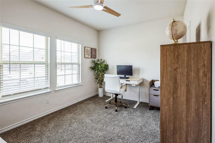 Carpeted office featuring baseboards and a ceiling fan