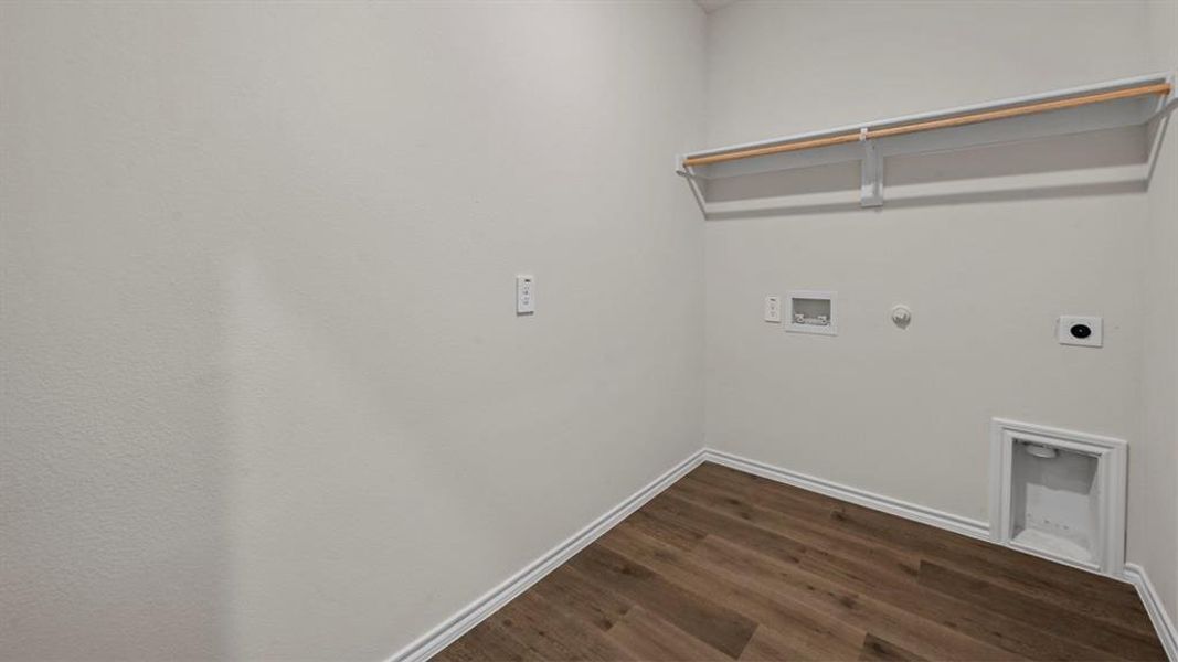 Dedicated laundry area featuring wood-finish flooring, white walls, and a built-in shelving unit with a hanging rod