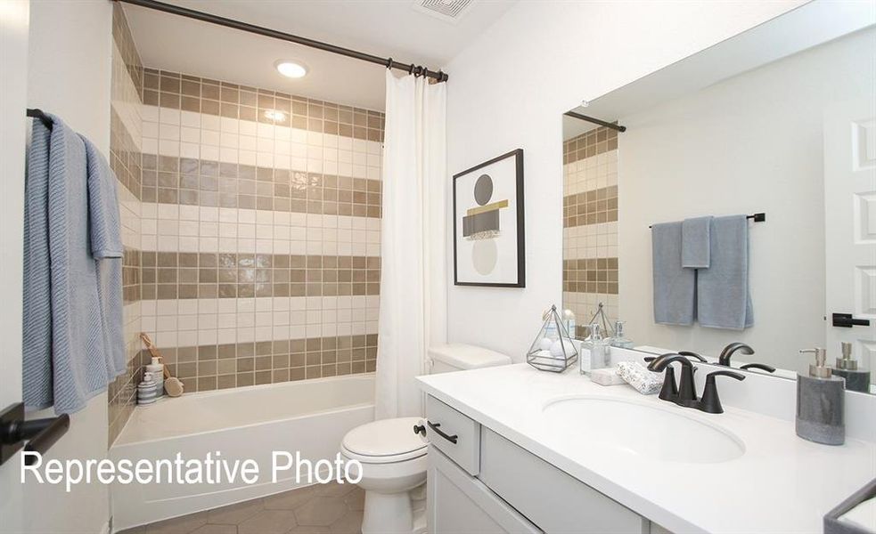 Full bathroom with tile patterned flooring, shower / bath combo with shower curtain, vanity, and toilet