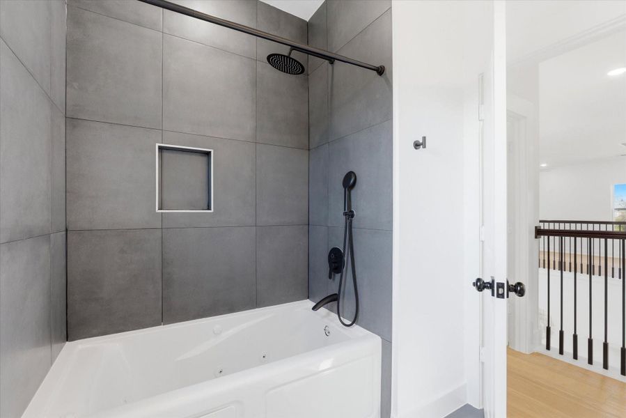 Bathroom located in the second floor features a relaxing jetted bathtub and shower combination, accented with sleek black shower heads for a modern touch.