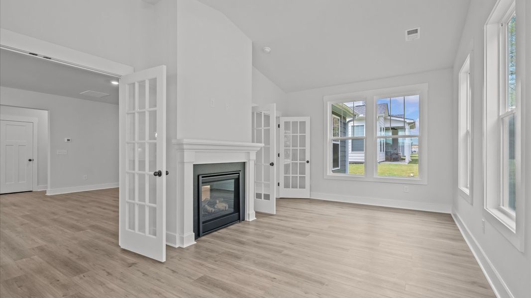 Elegant morning room featuring fireplace, hardwood flooring, large windows, and thoughtful architectural detail