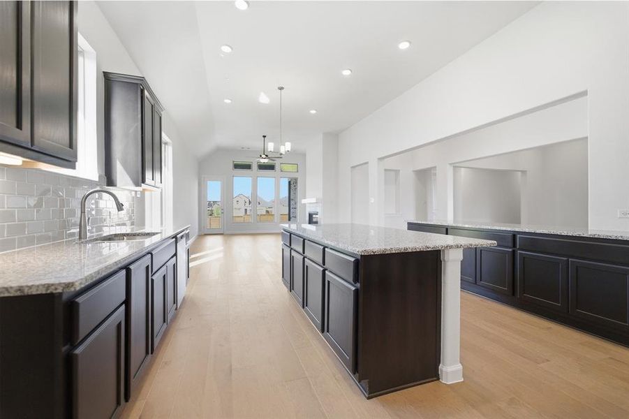 Contemporary kitchen featuring an expansive center island, dark cabinetry, and light speckled countertops