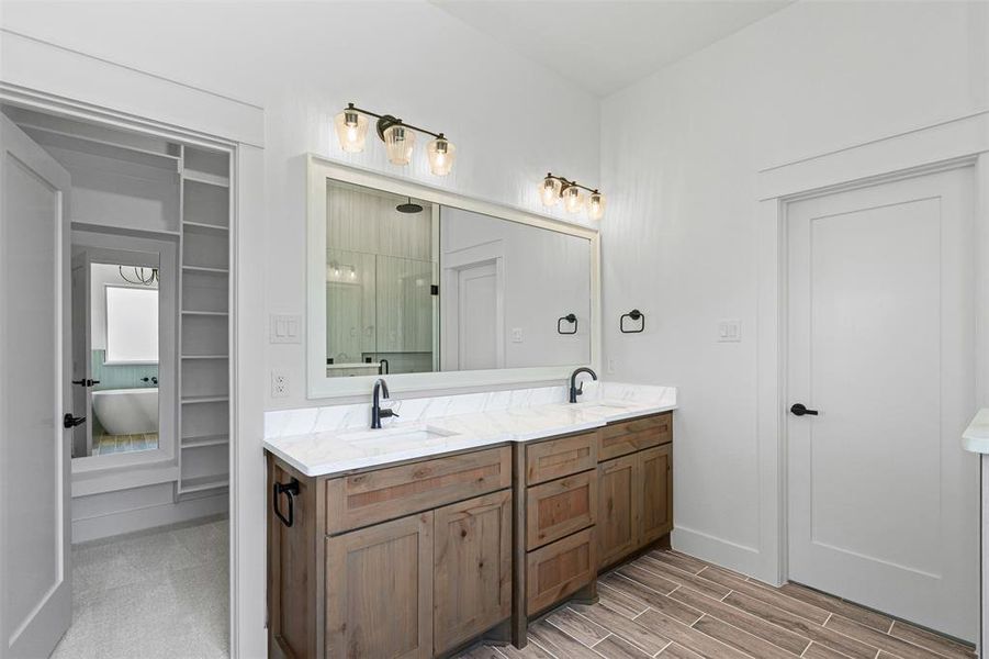 Bathroom featuring a shower stall, double vanity, wood tiled floors, and a soaking tub Bathroom featuring a shower stall, double vanity, wood tiled floors, and a soaking tub