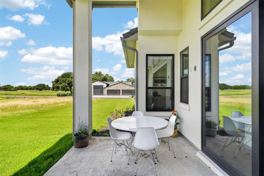 A tranquil outdoor patio with an al fresco dining set overlooks a verdant landscape. A tranquil outdoor patio with an al fresco dining set overlooks a verdant landscape.
