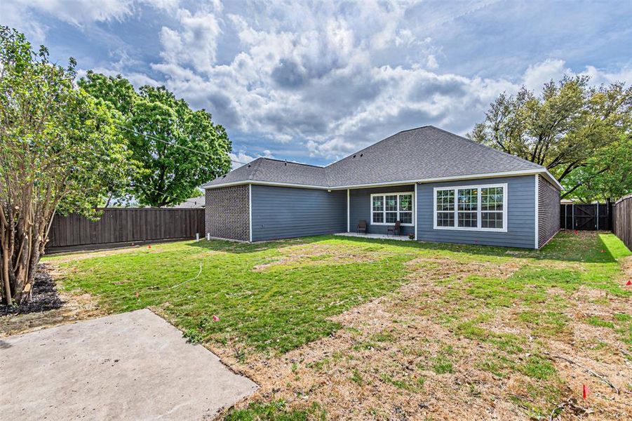 Expansive rear yard featuring a concrete patio, wood privacy fencing, and mature trees