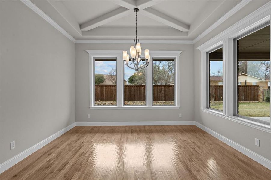 Unfurnished room with coffered ceiling, beamed ceiling, a notable chandelier, ornamental molding, and light hardwood / wood-style flooring  Not actual home. Previous built example.