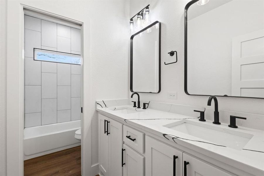 Full bathroom featuring hardwood / wood-style floors, toilet, vanity, and tiled shower / bath combo