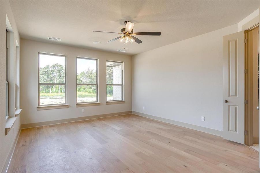 Unfurnished room with visible vents, ceiling fan, a wealth of natural light, and light wood finished floors