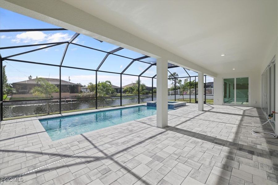 View of pool with a sunroom, a patio, a water view, a pool with connected hot tub, and glass enclosure