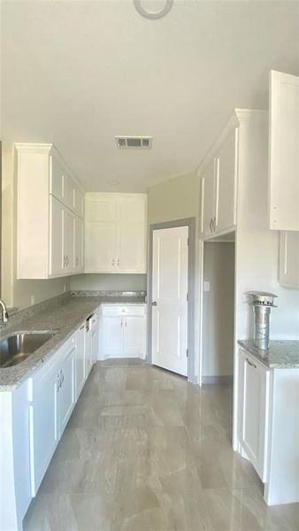 Kitchen featuring sink, light tile flooring, and white cabinetry