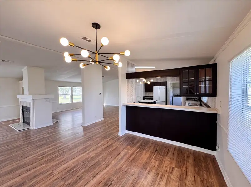 Rich wood flooring anchors this open layout connecting the main living areas and kitchen.